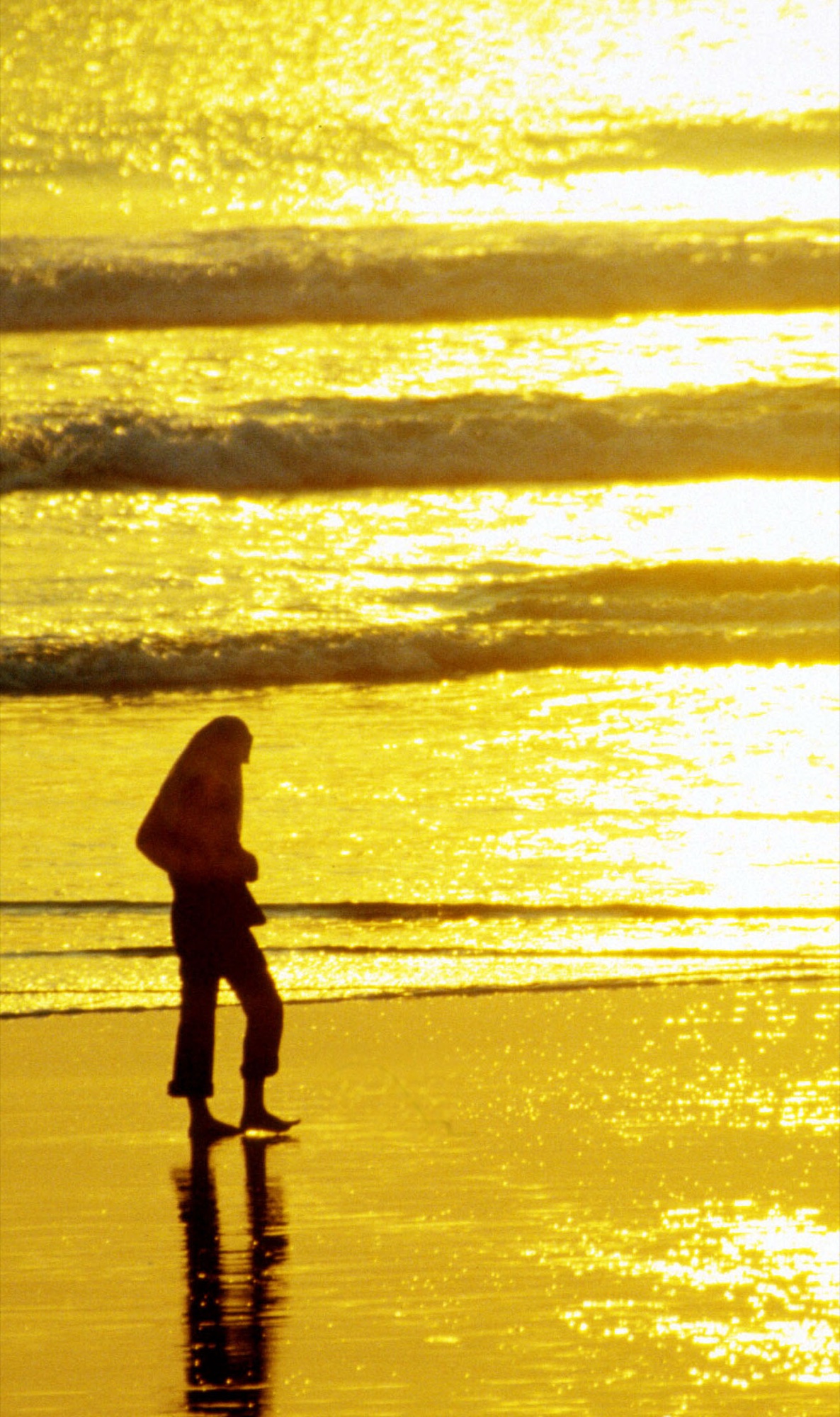 Silhouette of a beach wanderer against sunset reflections in Bali, Indonesia