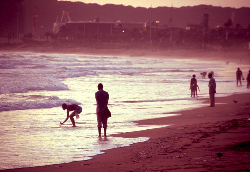 People walking along Durban beach at sunrise